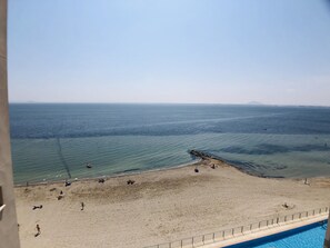 Una playa con vista despejada al mar, una orilla arenosa y una zona de piscina.