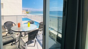 A balcony with a glass table and chairs, overlooking a swimming pool and a beach. - La Manga Beach Club - F (San Javier)