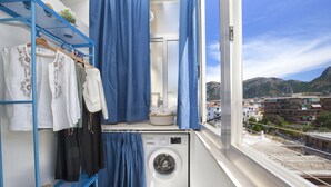 A laundry area with a washing machine, drying rack, and a view of the cityscape. - Alpa Suite (Sant'Agnello)