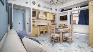 A compact living space with a kitchenette, a dining area, and a sofa. - Alpa Suite (Sant'Agnello)