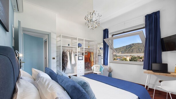 A bedroom with a bed, a desk, a TV, and a wardrobe. - Alpa Suite (Sant'Agnello)