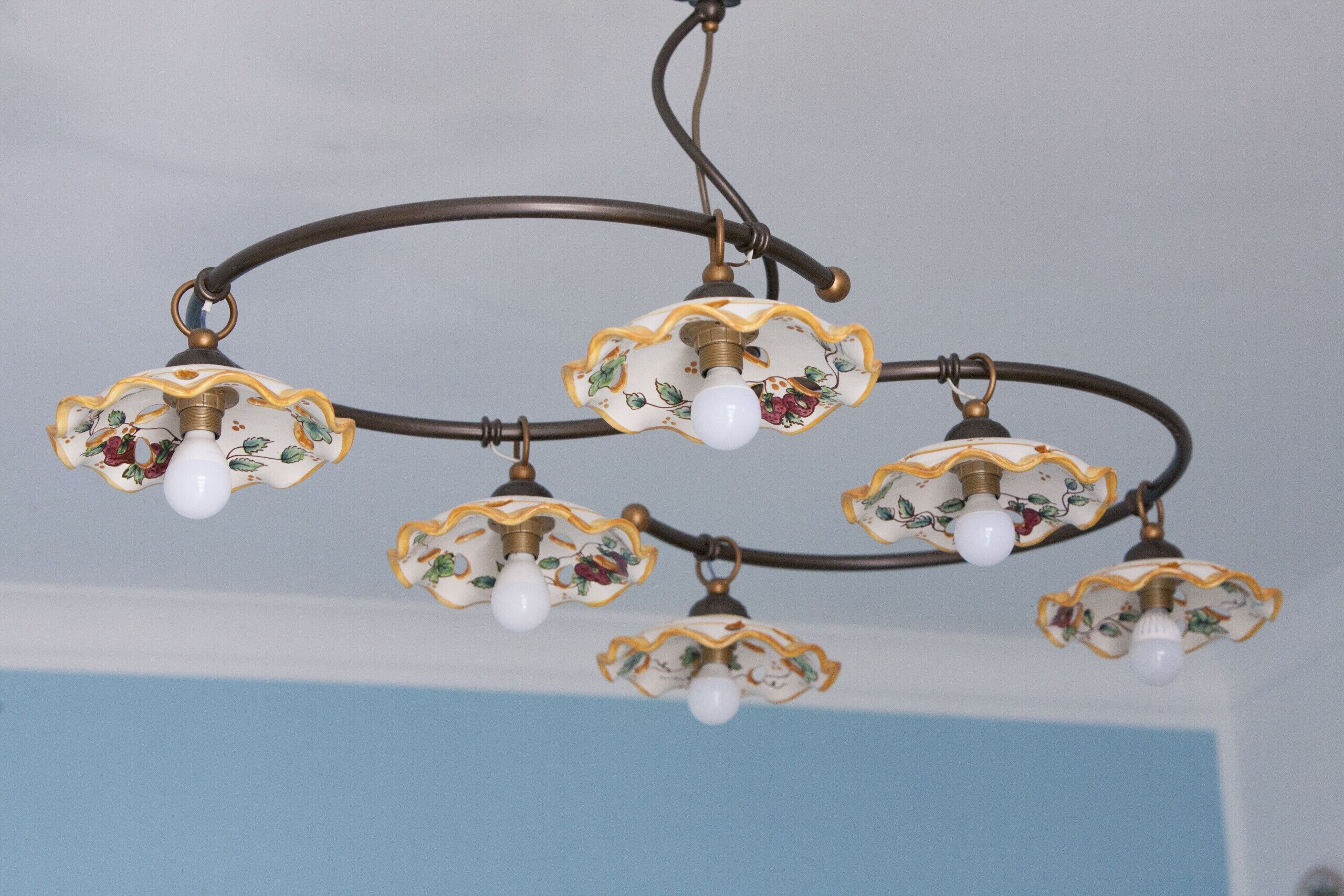 A chandelier with multiple light fixtures hanging from a curved metal structure.