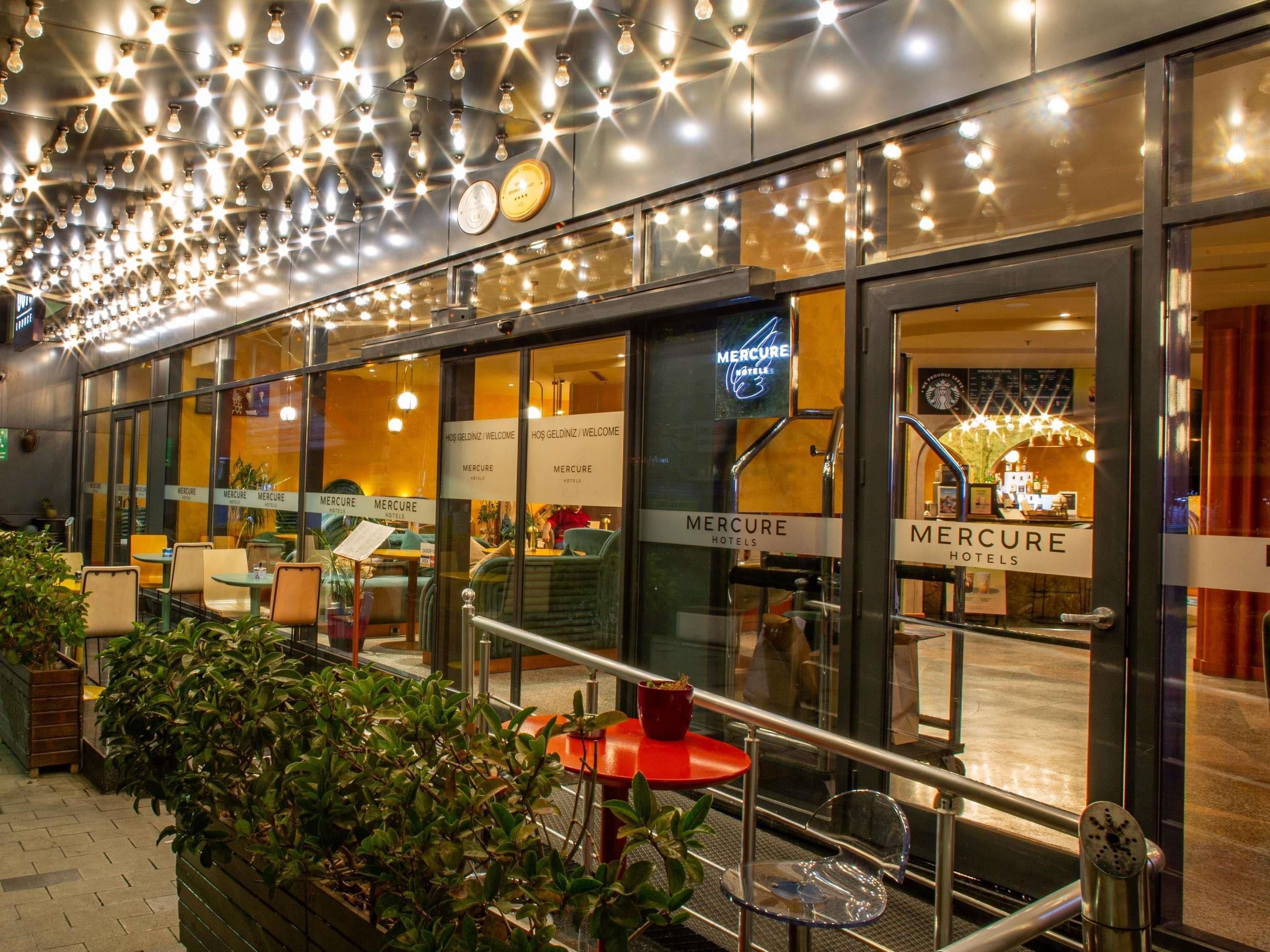 A hotel exterior with multiple seating areas, a staircase, and a sign indicating the hotel's name.