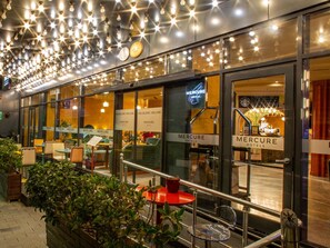 A hotel exterior with multiple seating areas, a staircase, and a sign indicating the hotel's name. - Mercure Istanbul Bakirkoy (Istanbul)