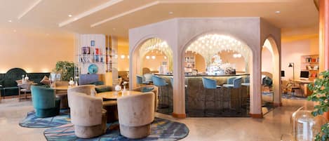 A modern hotel lobby with a bar area, seating, and a bookshelf.