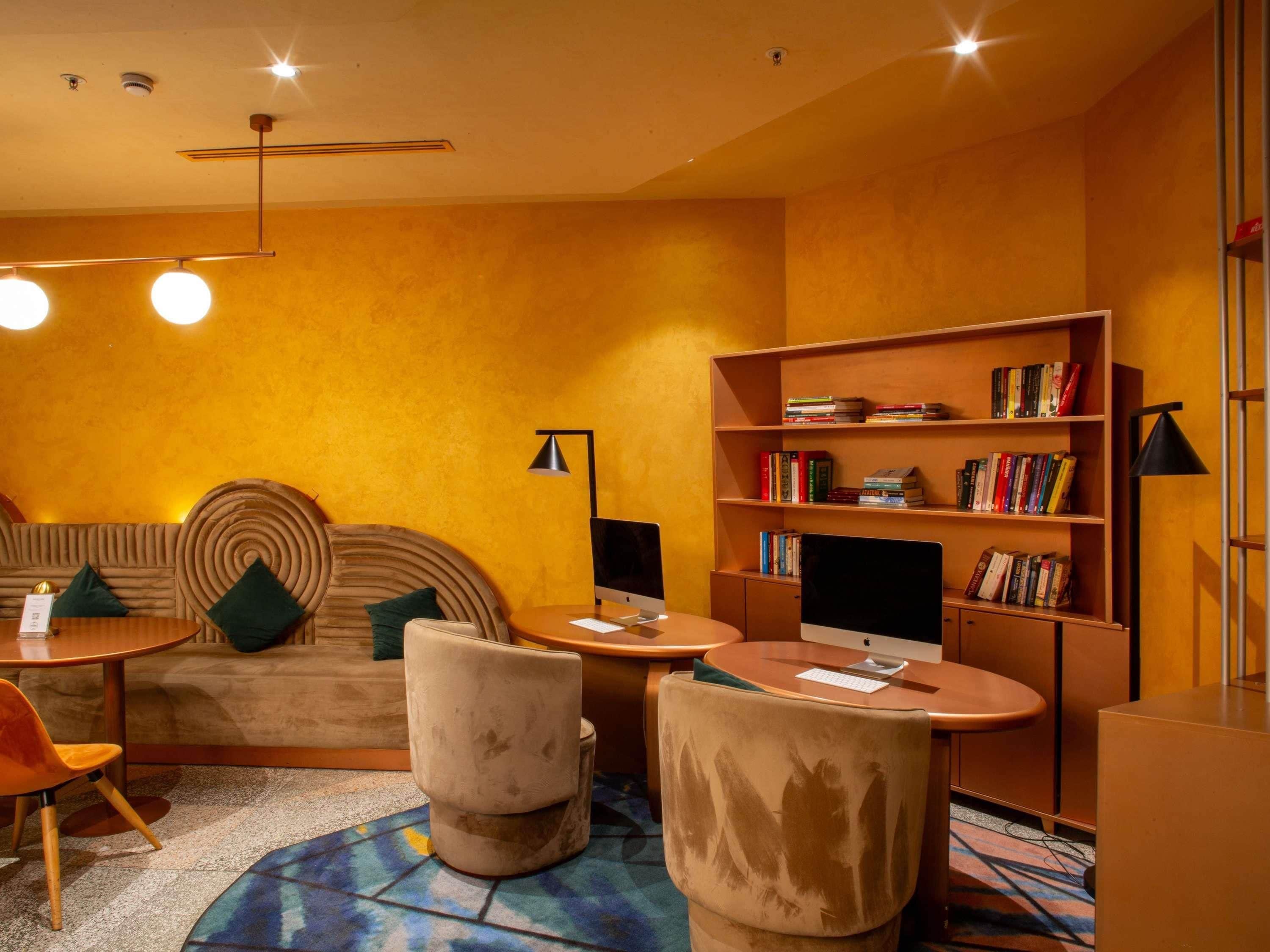 Une pièce confortable avec un canapé, des fauteuils, une bibliothèque et un bureau équipé d’un ordinateur.