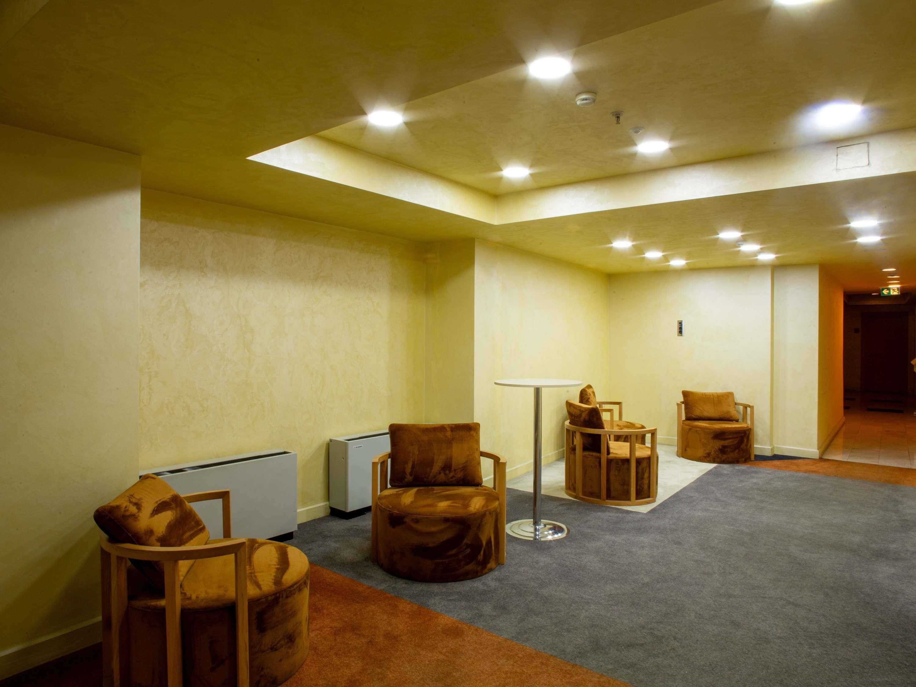 Ein Zimmer mit hoher Decke, eingelassener Beleuchtung, einem runden Tisch und mehreren Stühlen.