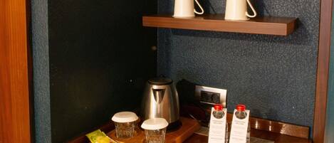 Una bandeja de madera con un bolígrafo, un paquete de pañuelos y dos botellas de agua sobre una mesa.
