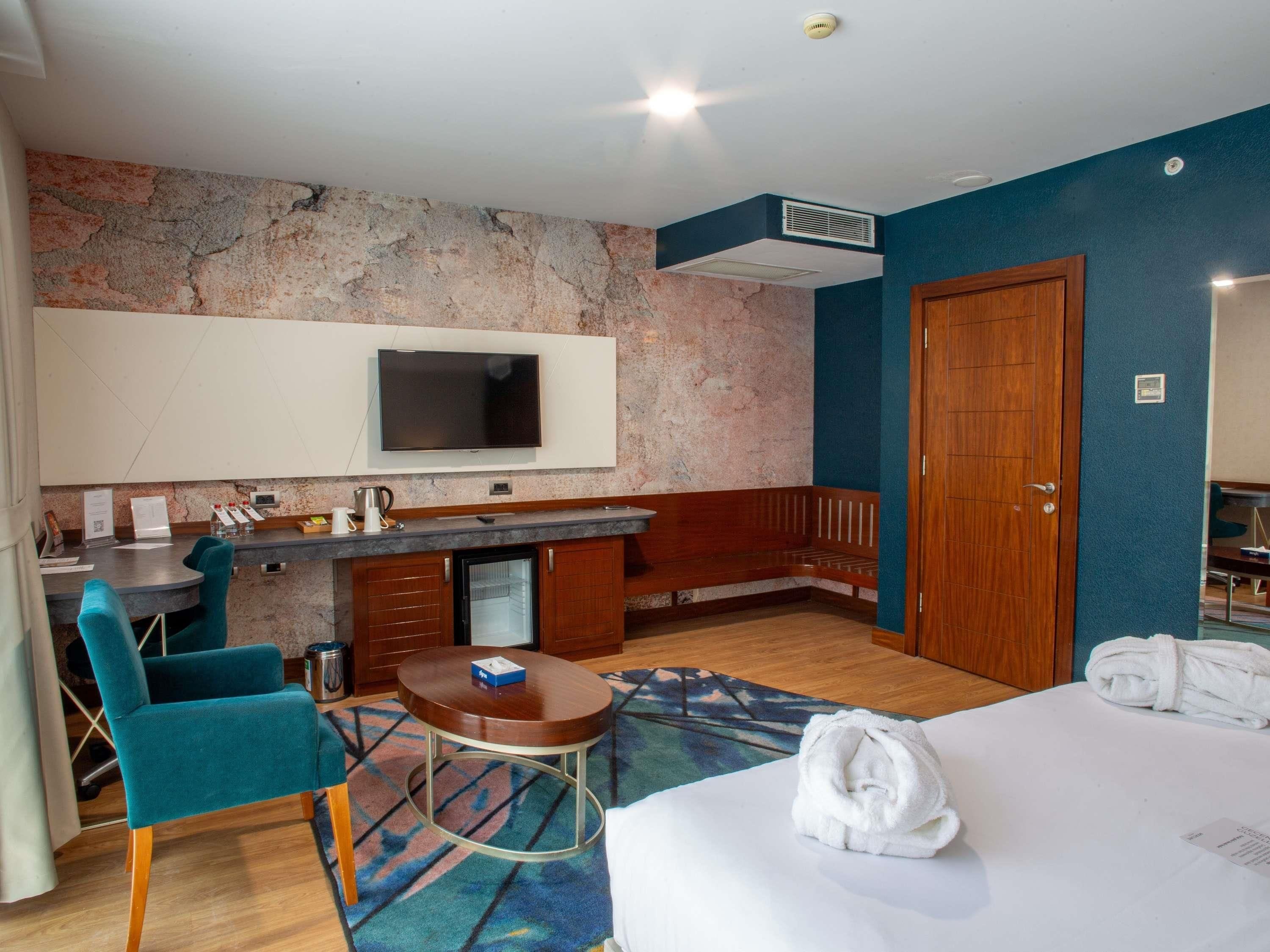 Una habitación de hotel con cama, escritorio, silla, televisor y baño.