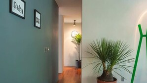 A hallway with a potted plant, framed pictures on the wall, and a green sculpture. - Top Location Polanco by Mr.W (Mexico City)