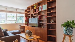 A living room with a sofa, a coffee table, a television, and a bookshelf filled with various items. - Top Location Polanco by Mr.W (Mexico City)