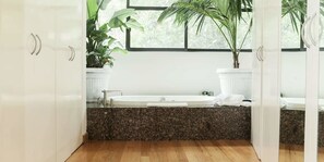 A modern bathroom with a freestanding bathtub, granite countertop, and potted plants.