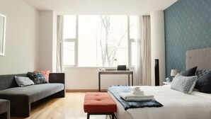 A modern bedroom with a bed, a sofa, a small table, and a window with curtains. - First Class Apartmet by Mr.W (Mexico City)
