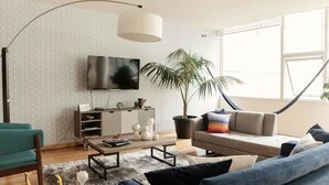 A modern living room with a sofa, armchair, coffee table, and a TV on the wall. - First Class Apartmet by Mr.W (Mexico City)