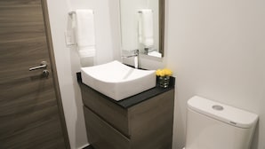 Un baño con lavamanos blanco, un espejo, un inodoro y una puerta de madera.