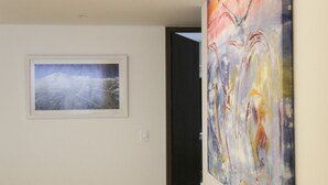 A hallway with a framed abstract painting on the left and a colorful abstract painting on the right. - Cactus Private Terrace by Mr.W (Mexico City)