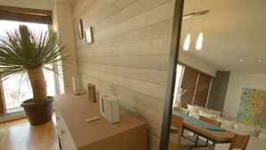 Ein modernes Interieur mit einem Holztisch, einer Topfpflanze und einem farbenfrohen abstrakten Gemälde an der Wand.