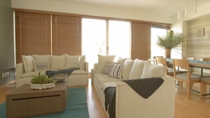 Ein modernes Wohnzimmer mit zwei Sofas, einem Couchtisch und einem Essbereich mit Tisch und Stühlen.