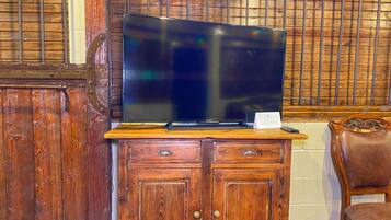A wooden cabinet with a flat-screen TV on top, a small card, and a remote control.