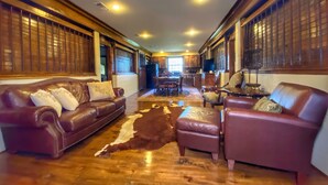 A spacious living room with leather sofas, a dining area, and a kitchen in the background. - Kiepersol Bed and Breakfast (Tyler)