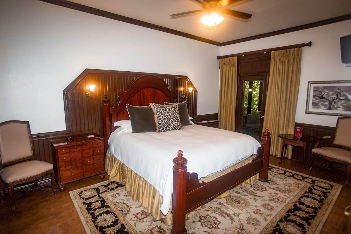 Une chambre à coucher de style traditionnel, avec un lit en bois, une commode, une chaise et une table de chevet.