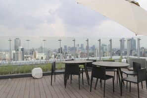 A rooftop terrace with a city view, featuring a round table and chairs, and a large umbrella. - City Vistas Apartment by Mr.W (Mexico City)