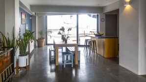 Une cuisine moderne avec un îlot central en bois, des tabourets de bar et des plantes en pot.