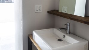 Une salle de bain moderne avec un lavabo blanc, un miroir et une étagère en bois.
