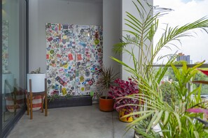 A balcony with a glass door, a chair, a potted plant, and a wall decorated with various stickers.
