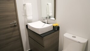 A bathroom with a white sink, a mirror, a toilet, and a wooden door. - Condesa Gem by Mr.W (Mexico City)