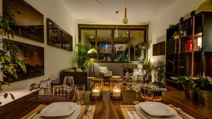 A dining area with a wooden table set for four, surrounded by potted plants and artwork. - Zen Modern by Mr.W (Mexico City)