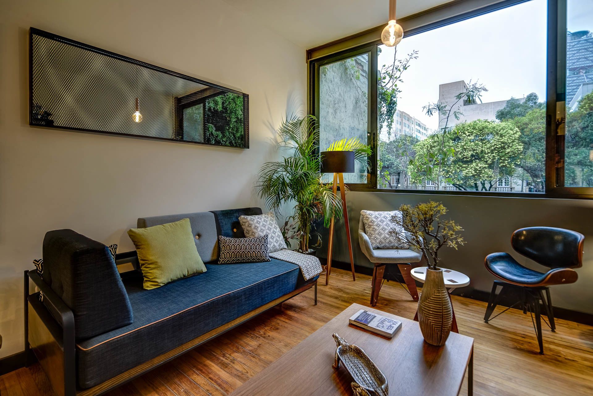 Ein modernes Wohnzimmer mit einer Couch, Sesseln, einem Couchtisch und einem großen Fenster mit Blick auf die Stadt.