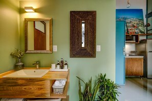 A bathroom with a wooden vanity, a large mirror, a sink, and a potted plant. - Zen Modern by Mr.W (Mexico City)