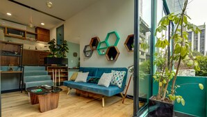 Un salon moderne avec un canapé bleu, une table basse en bois et une grande fenêtre donnant sur un paysage verdoyant.