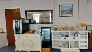 Hotelkamer met kitchenette, koelkast, magnetron, koffiezetapparaat, wastafel en een eethoek met een buffetopstelling.