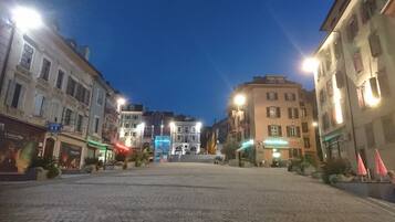 A cobblestone street lined with historic buildings, a central staircase, and outdoor seating areas.