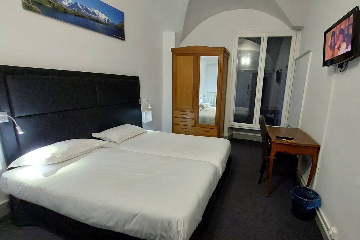 Een hotelkamer met een bed, een bureau, een stoel, een kledingkast en een televisie.
