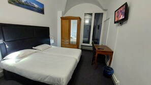 Une chambre d’hôtel équipée d’un lit, d’un bureau, d’une chaise, d’une armoire et d’un téléviseur.