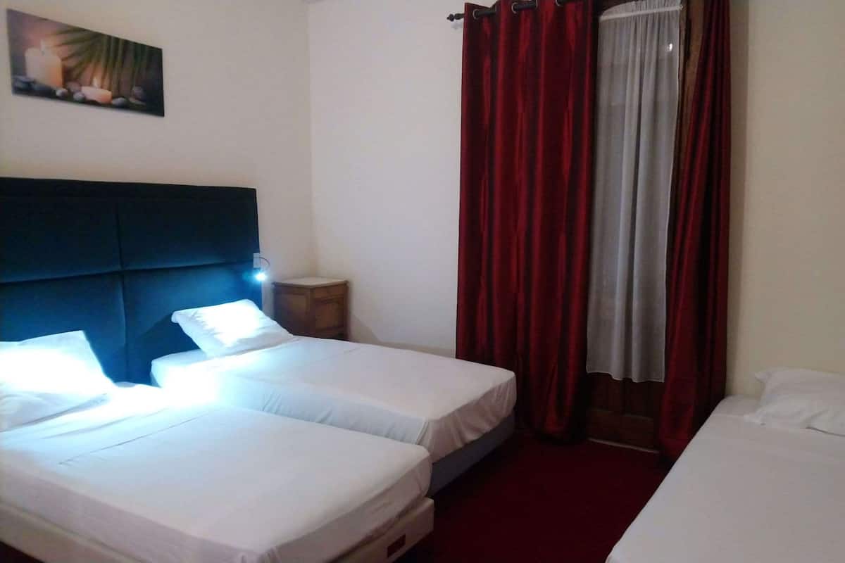 Een hotelkamer met twee eenpersoonsbedden, een nachtkastje, een hoofdbord en een schilderij aan de muur.