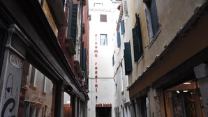 A narrow street with buildings on either side, a café at the end, and a visible sign for 'Café Bistro'. - DolceVita Apartments N. 118 (Venice)