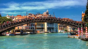 A historic bridge with pedestrians, a canal, and buildings in the background. - DolceVita Apartments N. 118 (Venice)