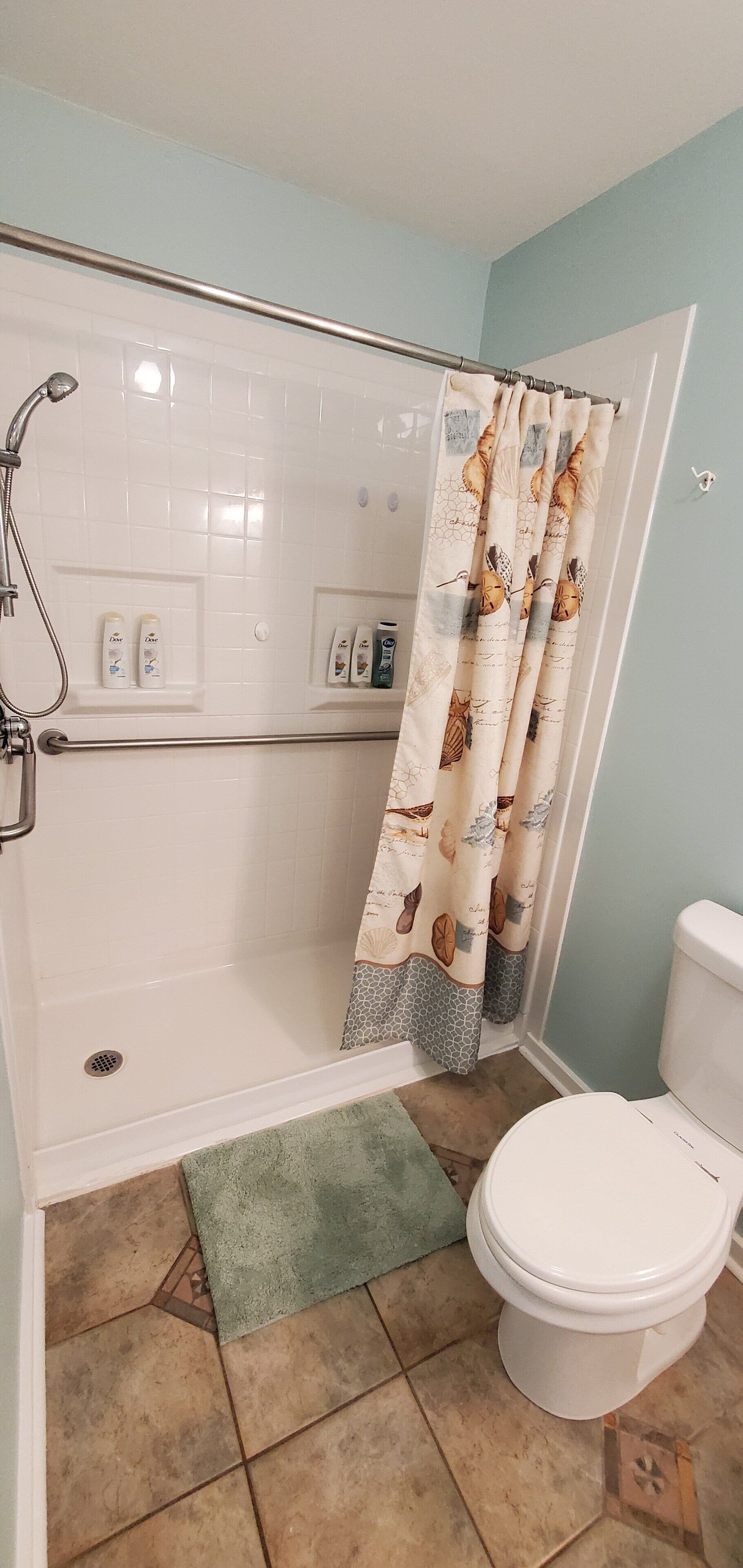Un baño con ducha, inodoro y perchero para toallas.