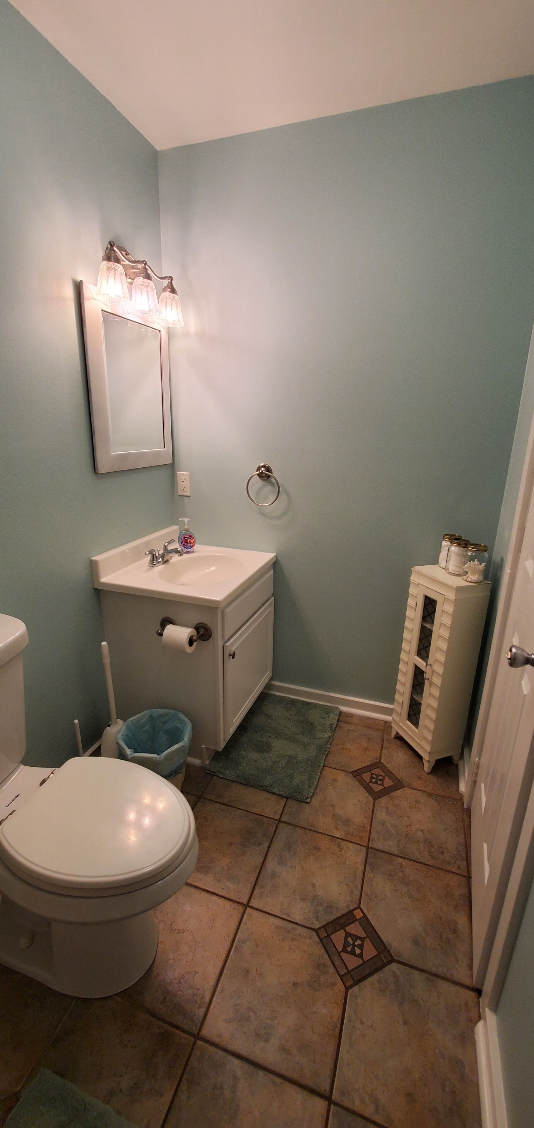 A bathroom with a toilet, sink, and mirror.