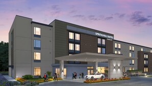 Un hotel moderno con techo plano, entrada cubierta y un cartel que dice "SPRINGHILL SUITES MARRIOTT".