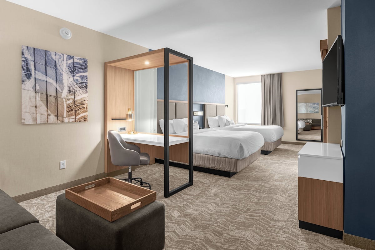 Een hotelkamer met een bed, een bureau, een stoel, een televisie en een schilderij aan de muur.