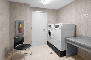 A laundry room with a washing machine, dryer, and a fire extinguisher on the wall.