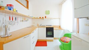 A modern kitchen with white cabinets, a wooden countertop, and a green stool. - DolceVita Apartments N. 146 (Venice)