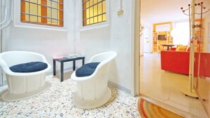 A room with two white armchairs, a small table, and a red sofa in the background. - DolceVita Apartments N. 146 (Venice)