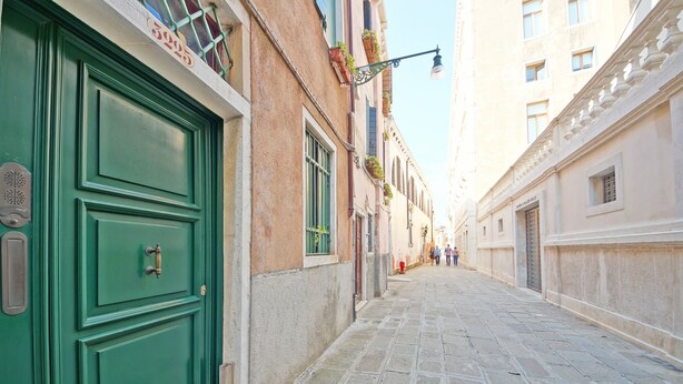 A narrow cobblestone street with a green door on the left and a building with a balcony on the right. - DolceVita Apartments N. 146 (Venice)
