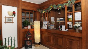 A reception area with wooden paneling, a post office counter, and various informational signs. - Hotel Bucaneve (Moena)